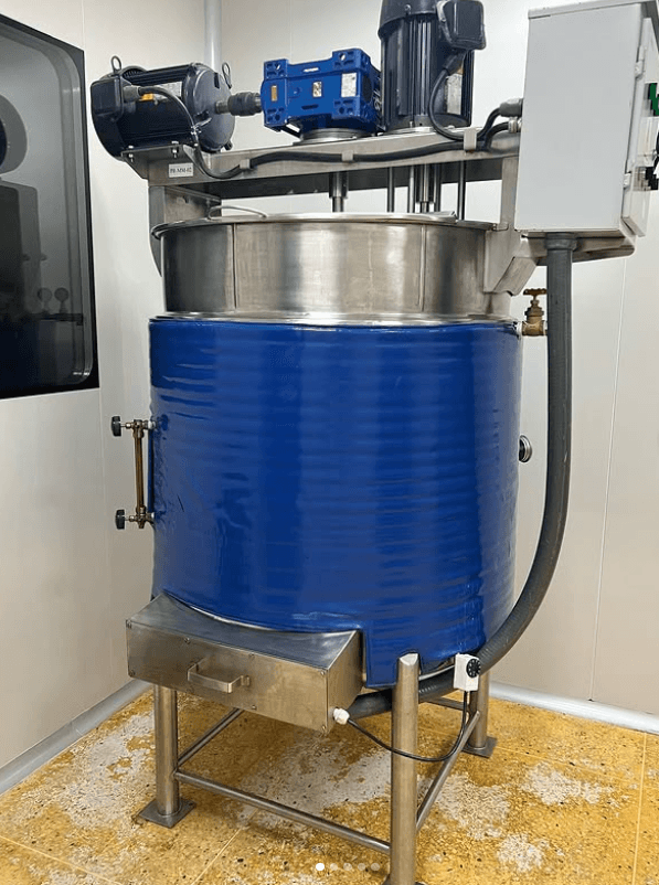 Tanque de mezcla industrial de acero inoxidable con camisa aislante azul y motores superiores.