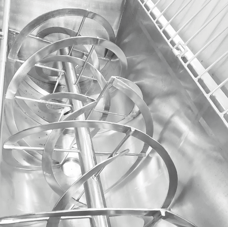 Mezcladora industrial de acero inoxidable con aspas en espiral dentro de un contenedor metálico brillante.