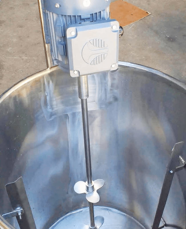 Mezclador industrial de acero inoxidable con motor superior y hélice de tres aspas en tanque.