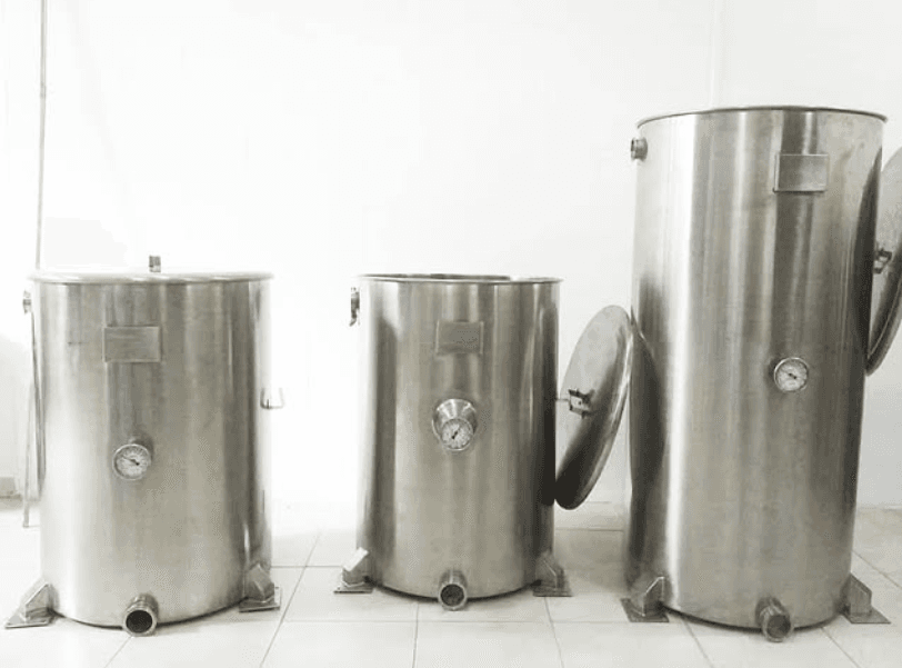 Tres tanques cilíndricos de acero inoxidable de distintos tamaños con manómetros y válvulas inferiores.