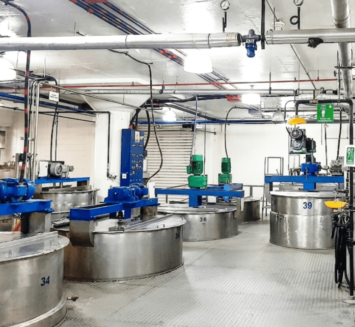 Tanques industriales de acero inoxidable numerados con motores azules y tuberías en una fábrica.